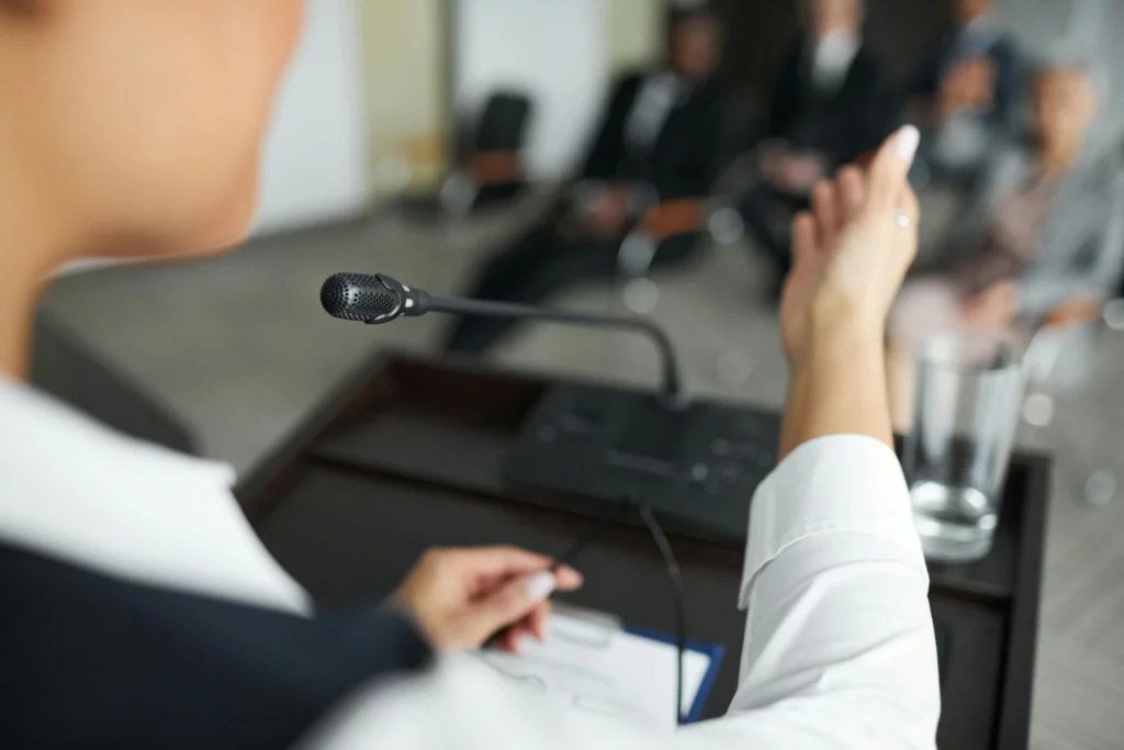 Photo d'une femme faisant un discours en réunion. Écriture sur mesure propose la rédaction de discours professionnels.