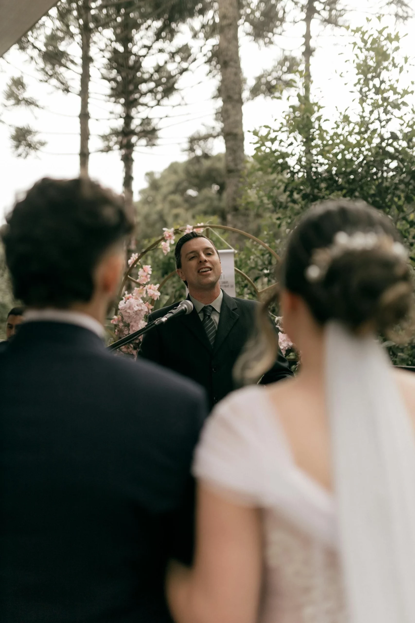 Photo d'un homme faisant un discours devant deux jeunes mariés. Écriture sur mesure propose la rédaction de discours de mariage.