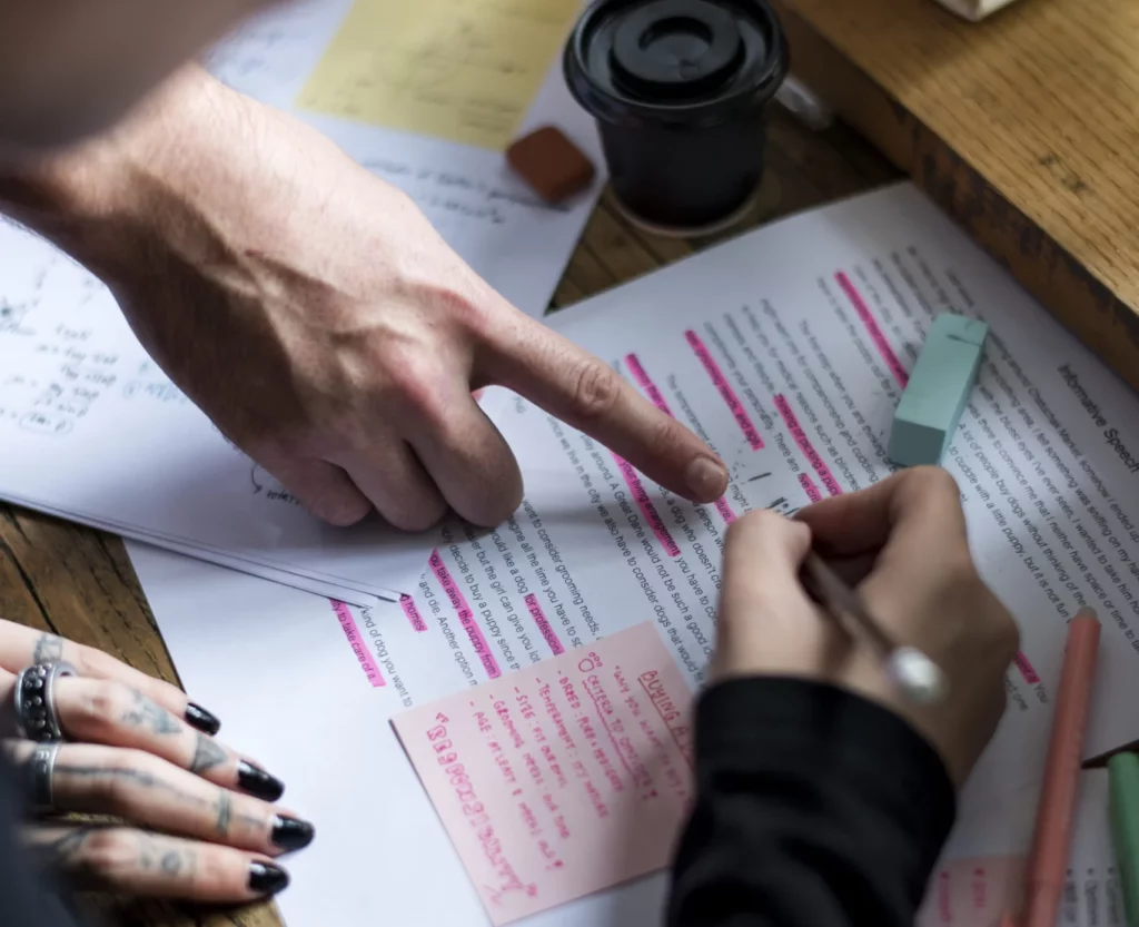 Une main pointe des corrections en rouge sur un texte. C'est l'un des services pour les particuliers que je propose.